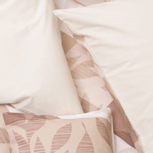 Detalle de ropa de cama blanca y rosa con estampado geométrico